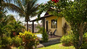 Une maison dotée d’un patio, entourée d’une végétation luxuriante et d’un palmier.