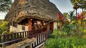 Un bâtiment à toit de chaume, doté d’une terrasse en bois et d’une enseigne indiquant qu’il s’agit d’un restaurant.