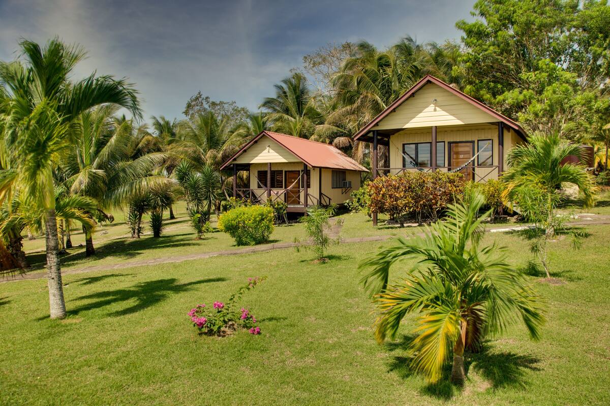 A bungalow-style hotel with a thatched roof, surrounded by lush greenery and palm trees.