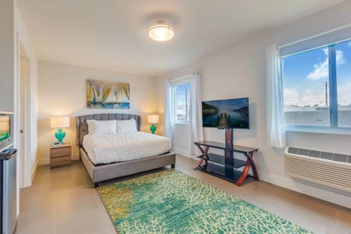 A bedroom with a bed, bedside tables, a TV, and a window with a view.