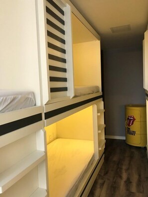 Una cama litera con colchón amarillo y un barril con vinilo de los Rolling Stones en la esquina.