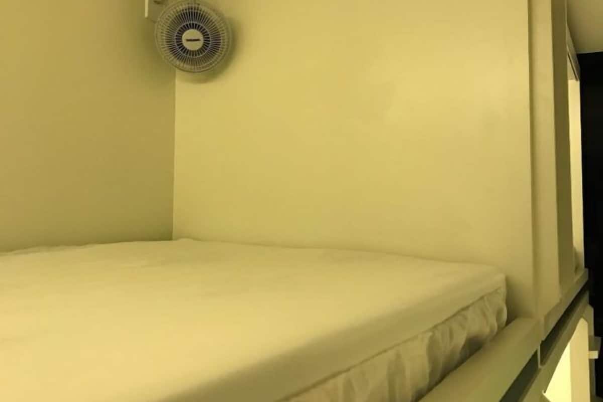 A bunk bed with a ceiling fan in a room with white walls.
