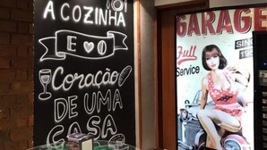 L’intérieur d’un restaurant avec un tableau noir servant de panneau, un tonneau vert et une affiche publicitaire représentant une voiture ancienne.