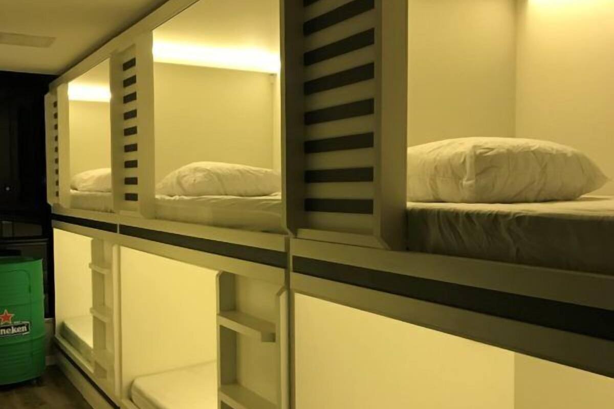 Bunk beds with built-in shelves, a green trash bin, and a wall-mounted light fixture.