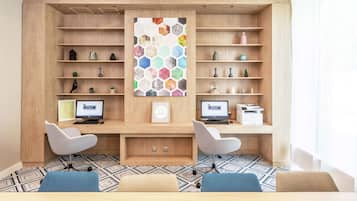 A modern office space with two desks, chairs, and a large wall-mounted shelf unit.