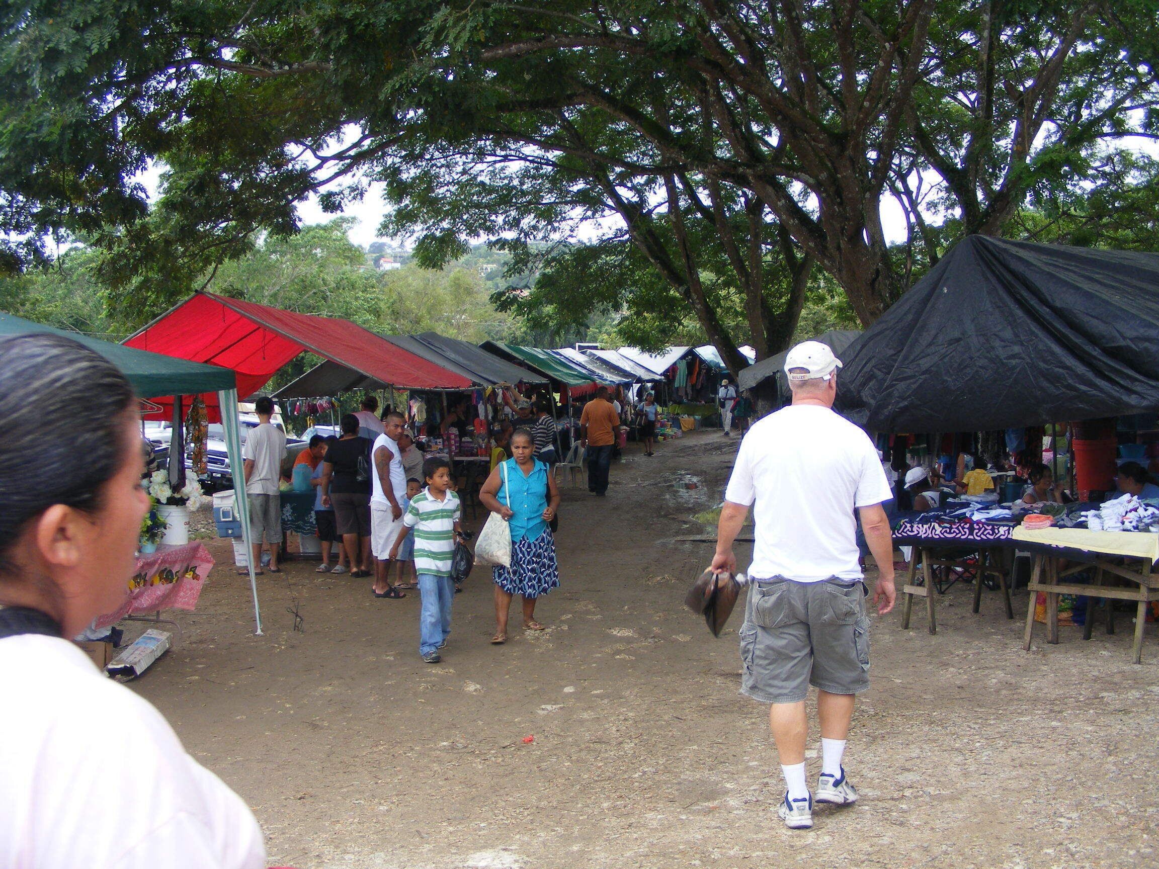 A market scene with people walking and vendors under tents.
