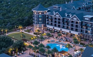 A resort with a swimming pool, outdoor seating, and a large building with multiple balconies. - The Henderson Lofts (Destin)