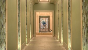 Un couloir doté d’un plancher en bois, d’un vase décoratif et d’une porte au fond.