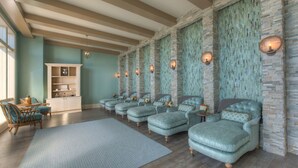 Une salle de spa avec une rangée de fauteuils turquoise, un meuble en bois et un grand tapis.