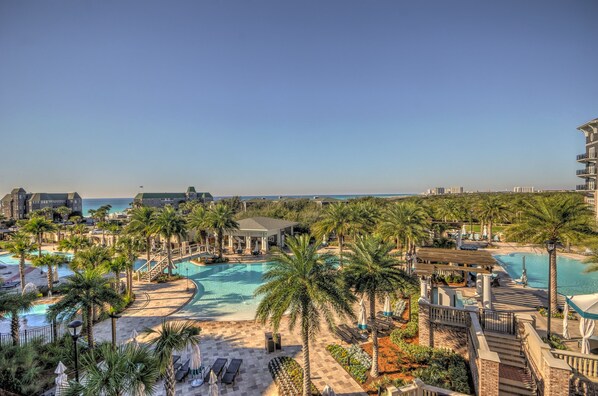 A resort with multiple swimming pools, palm trees, and a view of the ocean.