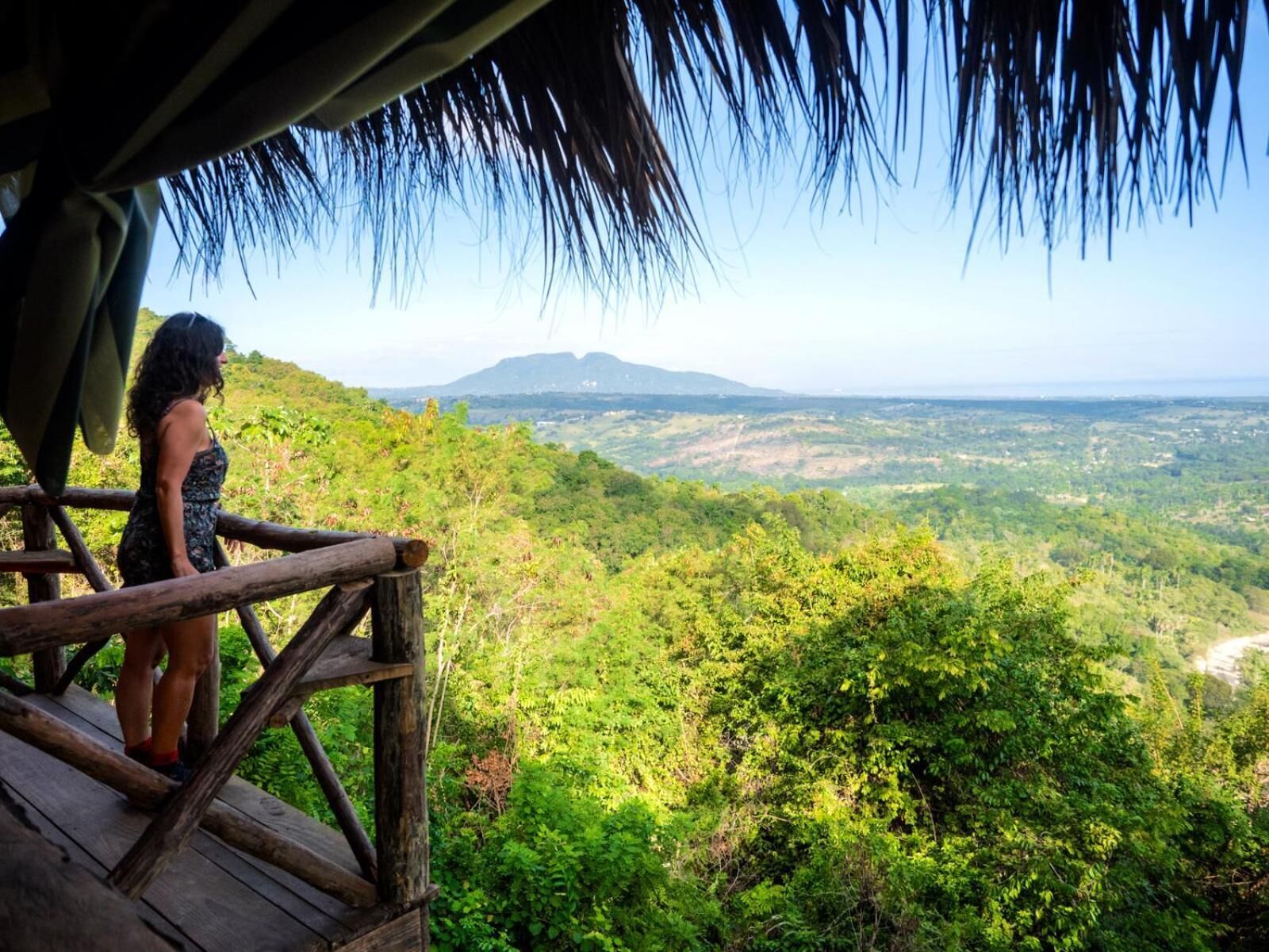 Una terraza de madera con vistas a un paisaje verde exuberante y una montaña al fondo.