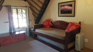 A cozy room with a wooden bed, a small wooden chest, a radiator, and a framed picture on the wall.