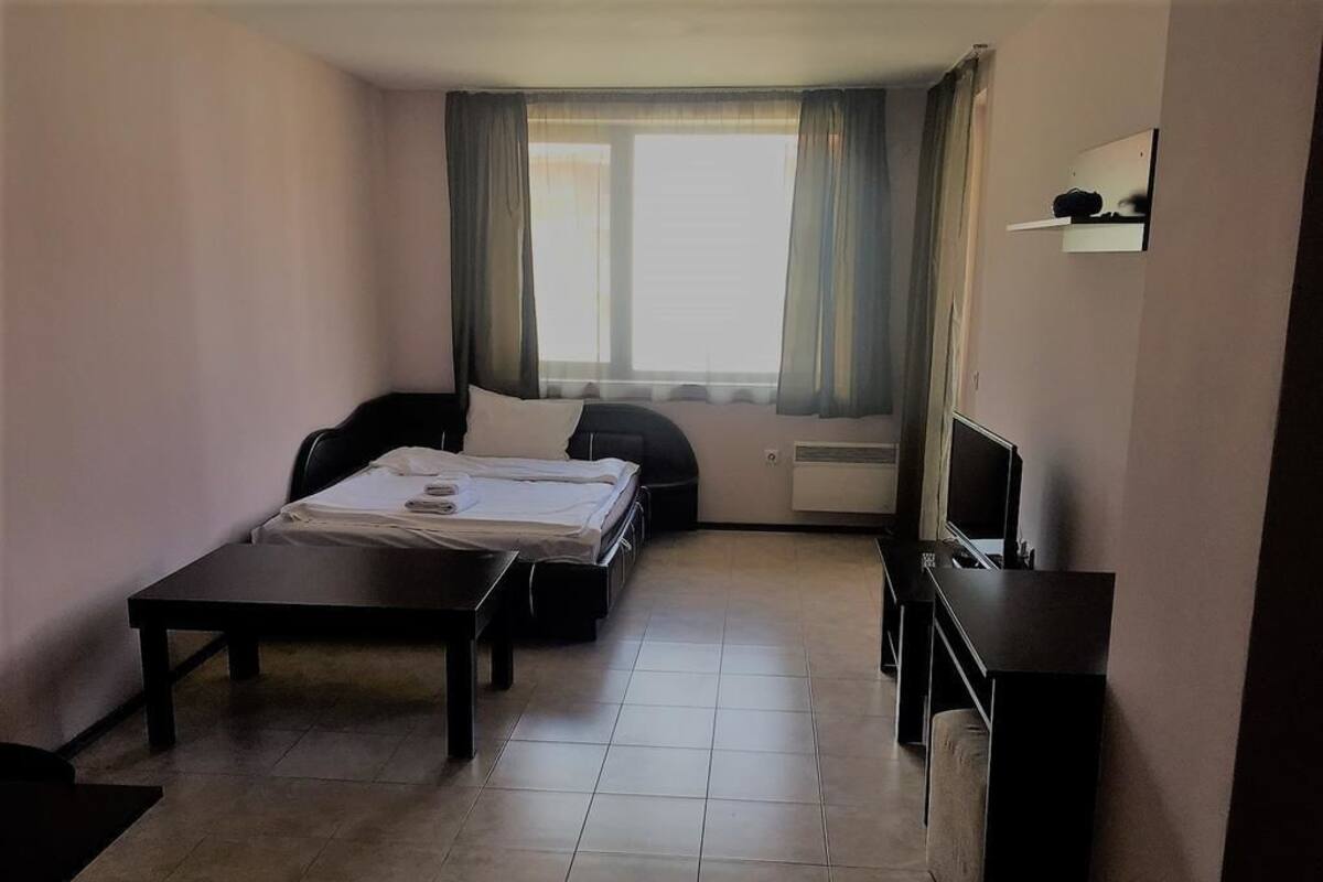 Habitación de hotel pequeña con cama, escritorio, una silla y televisor.