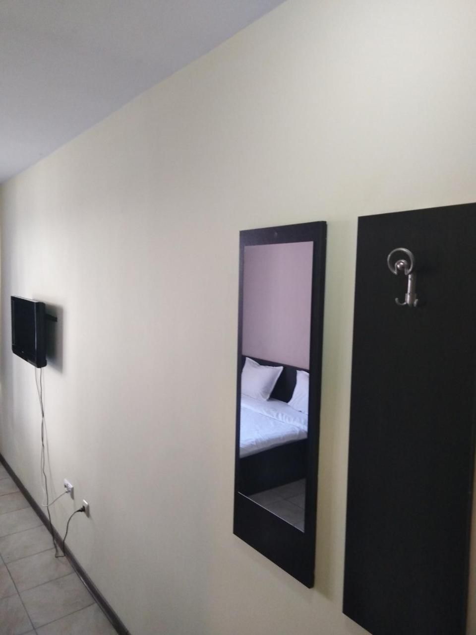 A hotel room with a bed, a TV mounted on the wall, and a door with a handle.