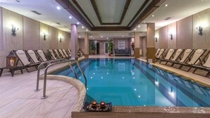 Una piscina con sillas de descanso y un suelo de baldosas.