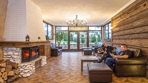 Un espacio de salón acogedor con chimenea de piedra, sofás de cuero y una araña.