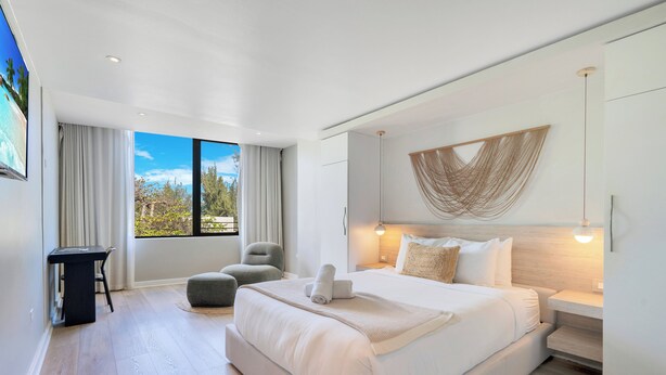 A modern bedroom with a large bed, a desk, and a view of the outdoors. - Hotel Mome (San Juan)
