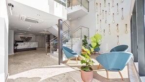 A spacious lobby with a marble floor, a staircase, and a reception desk. - Hotel Mome (San Juan)