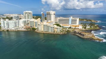 Un hotel costero con varios edificios altos, una playa y una estructura fortificada.