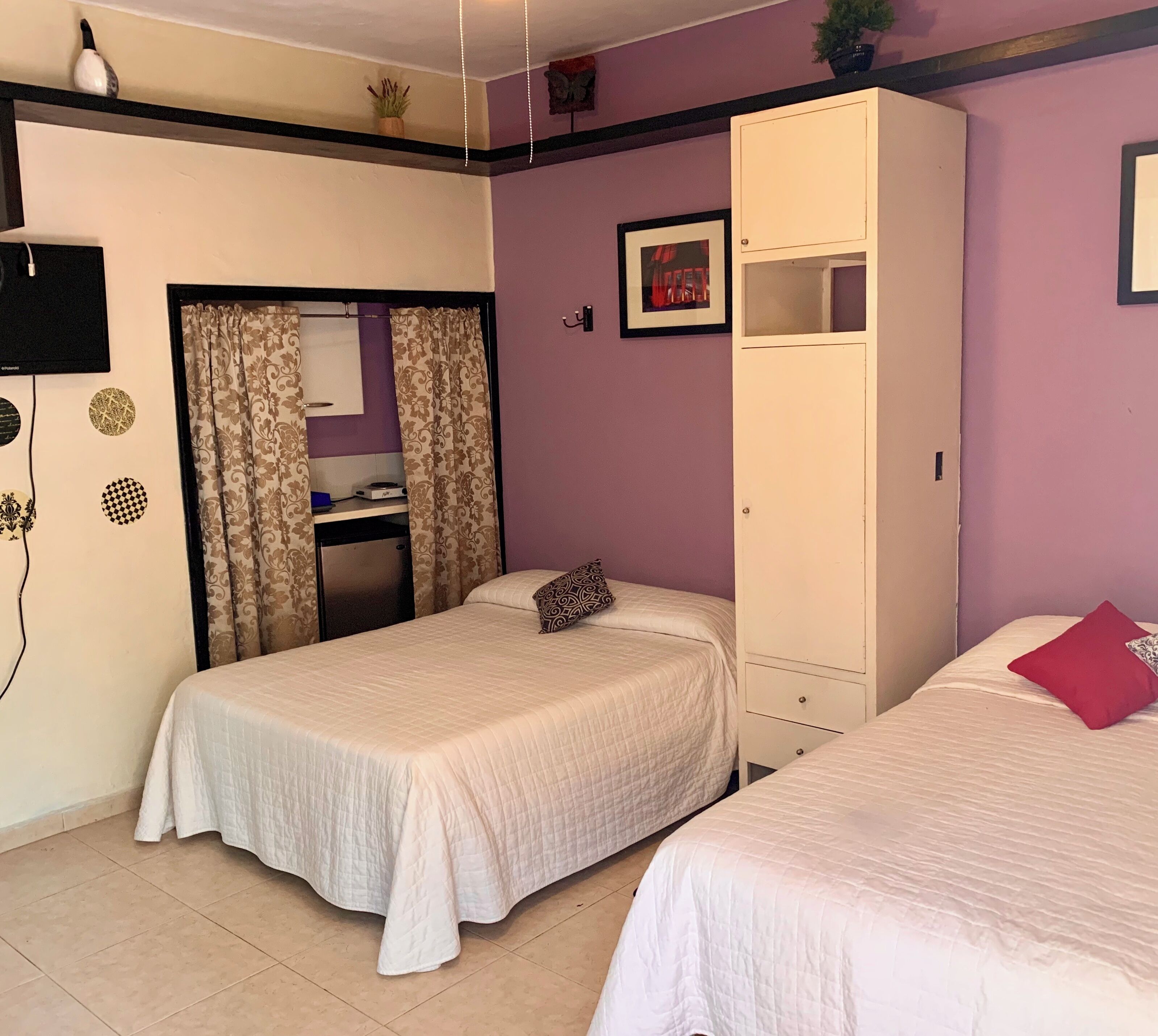 Quarto com duas camas, guarda-roupa, escrivaninha e espelho.