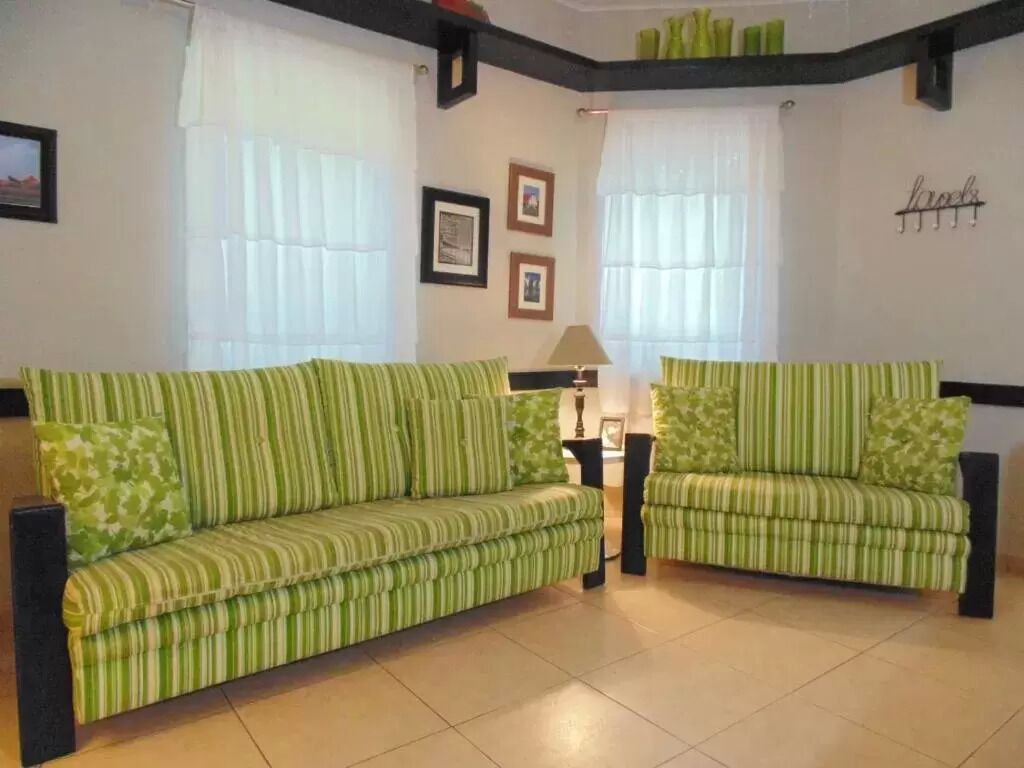 Ein Wohnzimmer mit zwei gestreiften Sofas, einer Lampe und gerahmten Bildern an der Wand.
