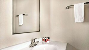 Ein Badezimmer mit einem weißen Waschbecken, einem Spiegel und einem Handtuchhalter.