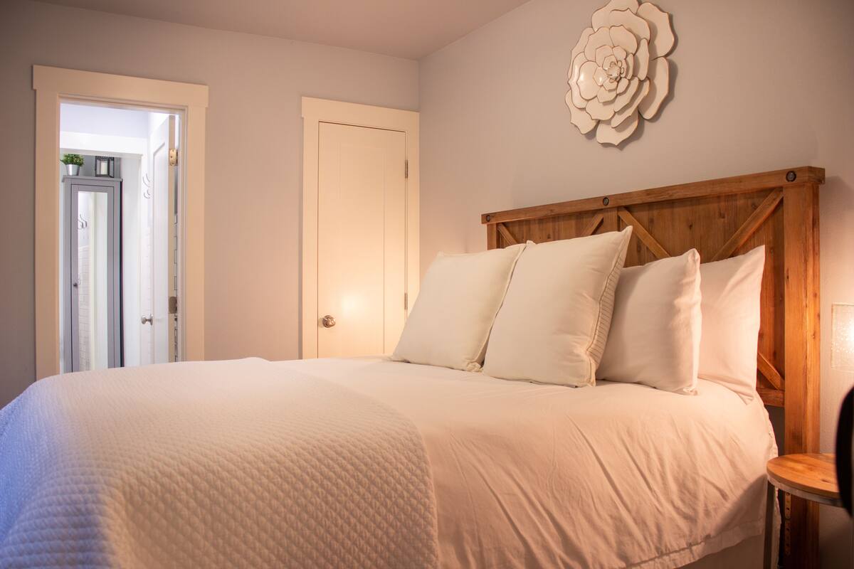 A bedroom with a large bed, a wooden headboard, and a wall-mounted decorative piece.