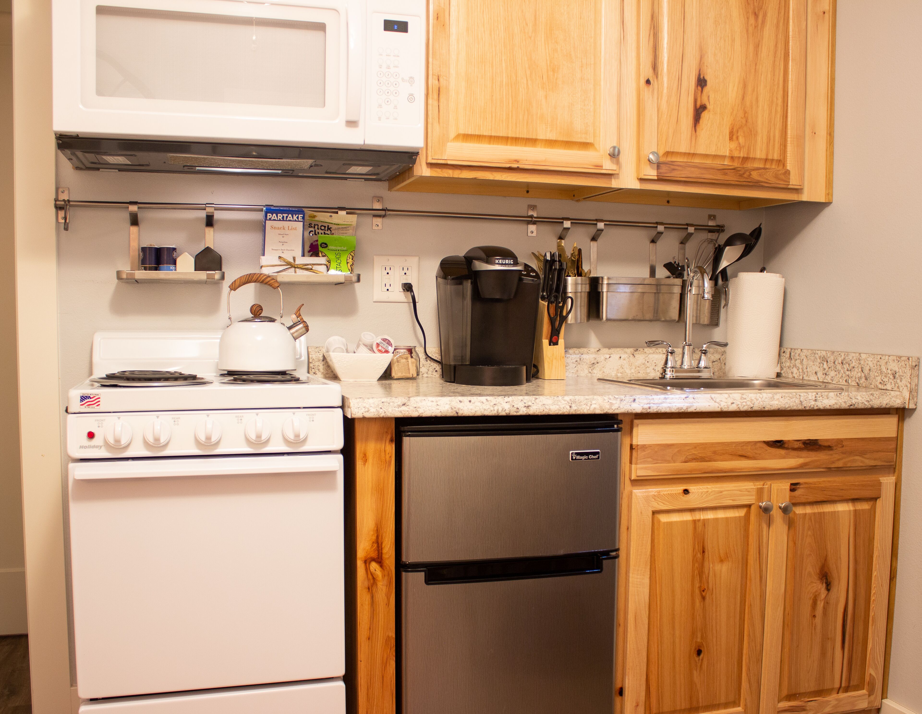 A compact kitchen with a stove, microwave, coffee maker, and dishwasher.