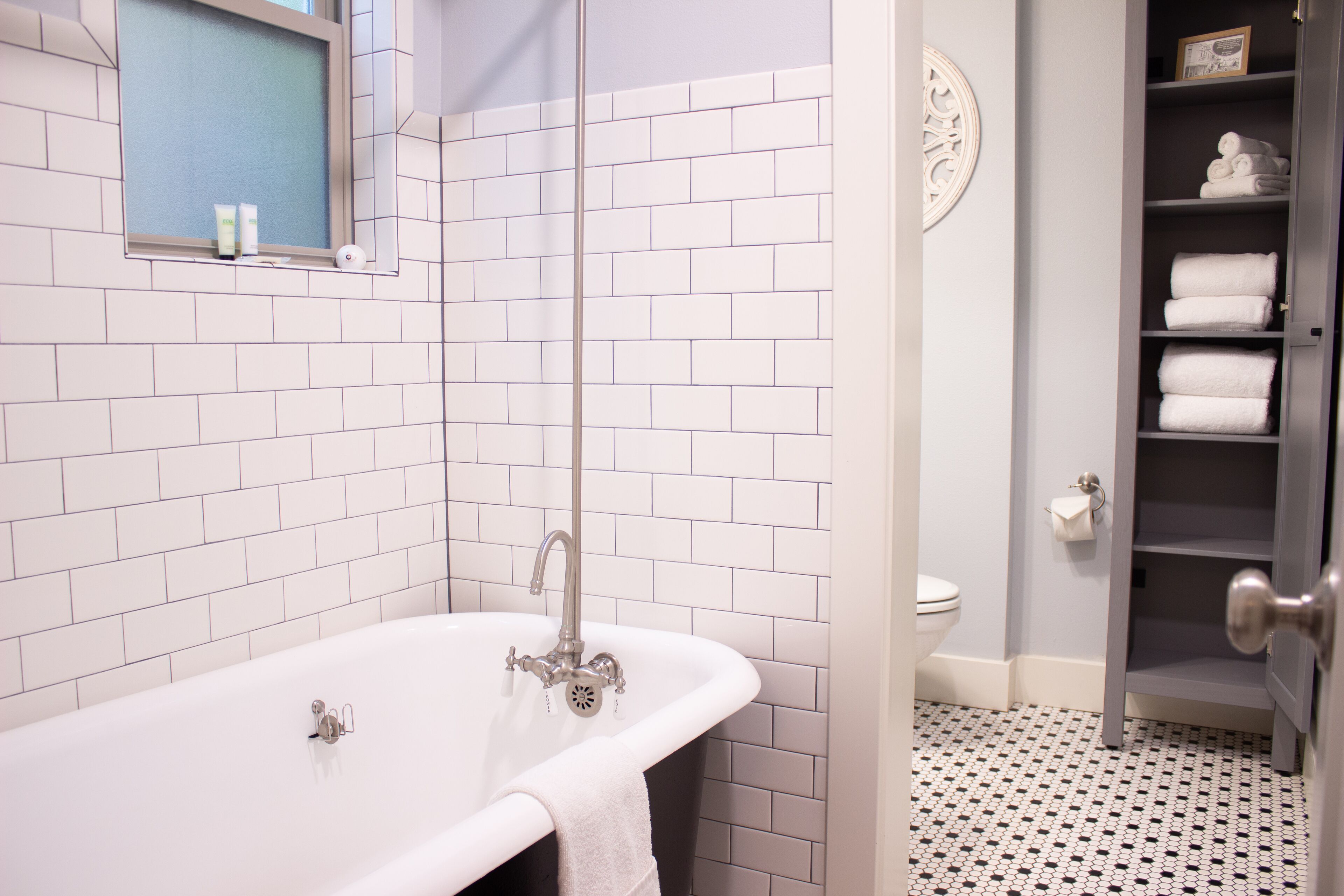 A bathroom with a white bathtub, a toilet, and a towel rack.