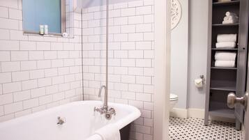 A bathroom with a white bathtub, a toilet, and a towel rack.