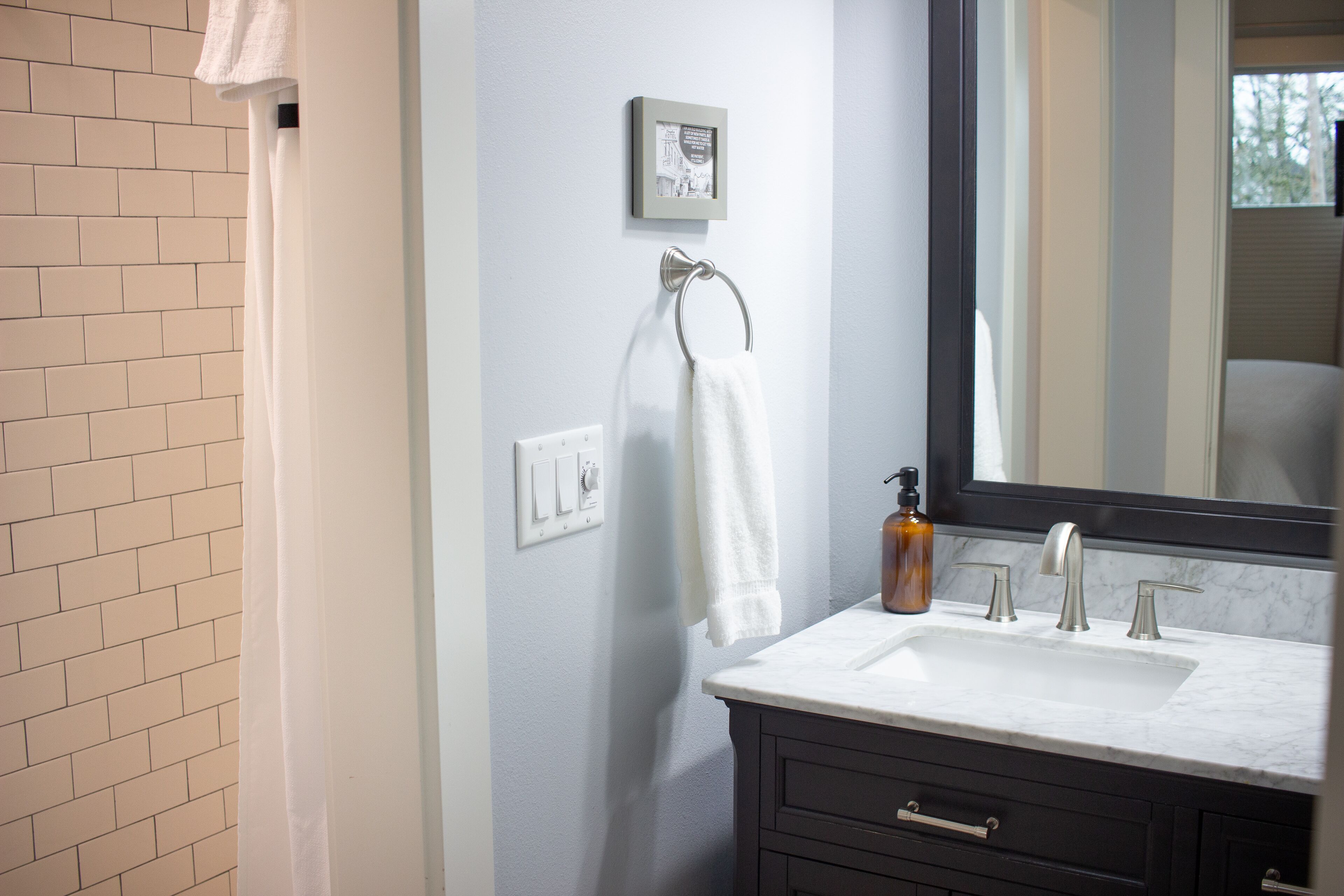 A bathroom with a white sink, dark wooden cabinet, and a large mirror.
