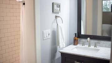 A bathroom with a white sink, dark wooden cabinet, and a large mirror.