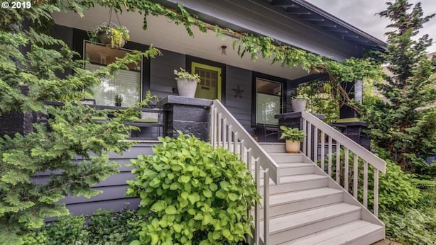 Une maison avec une véranda, des marches et des plantes en pot.