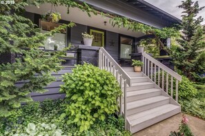 Una casa con porche, escalones y plantas en macetas.