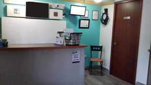 A reception area with a counter, a chair, a door labeled "Private," and a wall clock. - Hotel Ulúa (Veracruz)