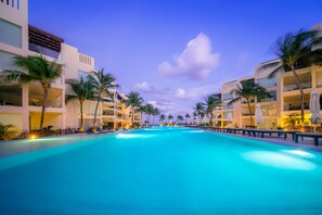 Una piscina al aire libre, sombrillas, sillones reclinables de piscina