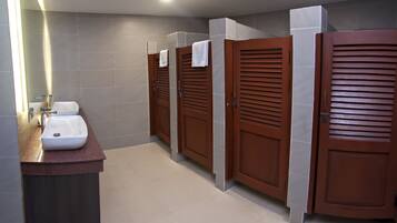 Un baño moderno con tres cabinas de madera, un lavabo y un espejo.
