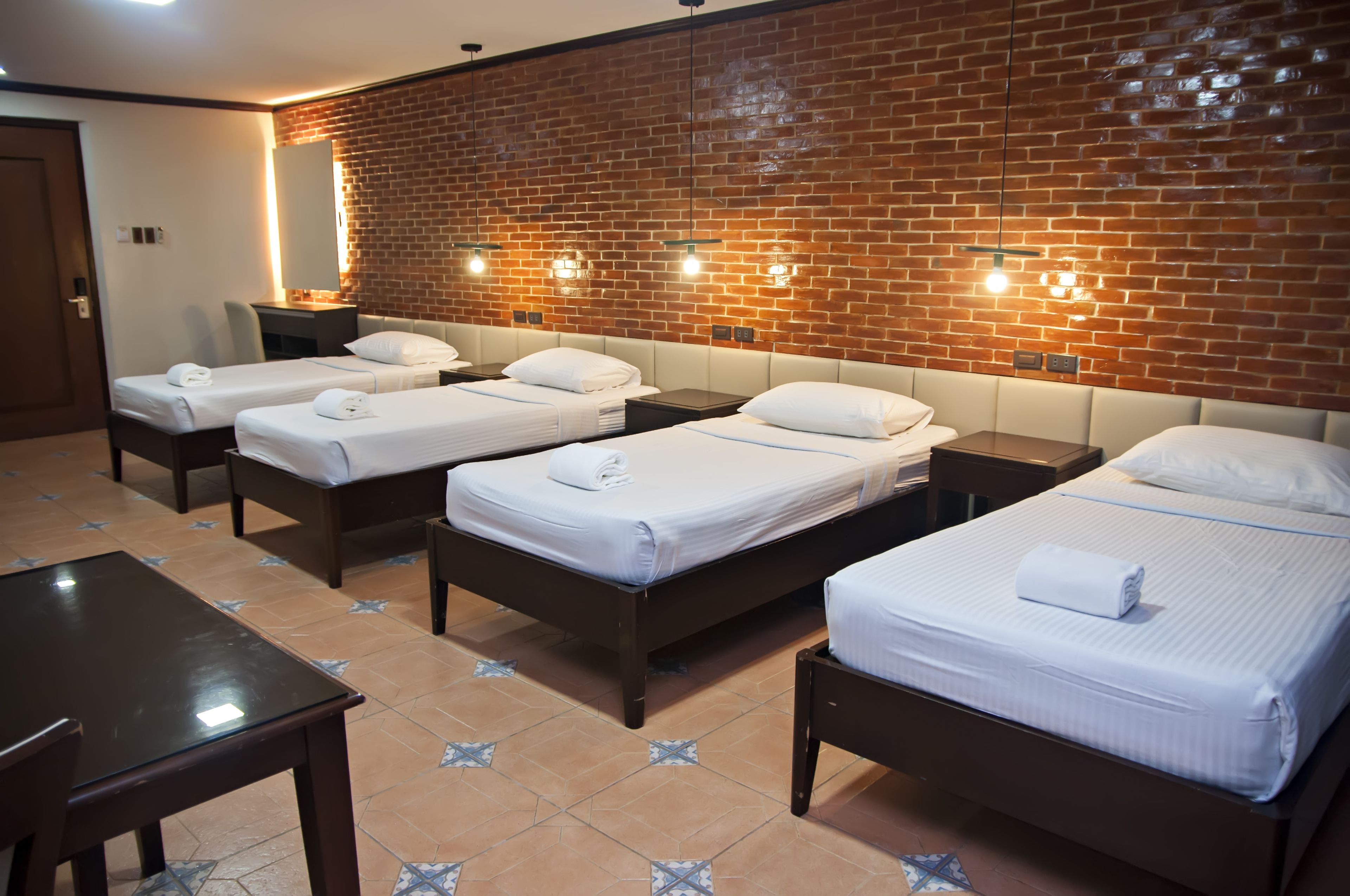 A hotel room with four single beds, a desk, and a chair.
