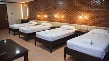 A hotel room with four single beds, a desk, and a chair.