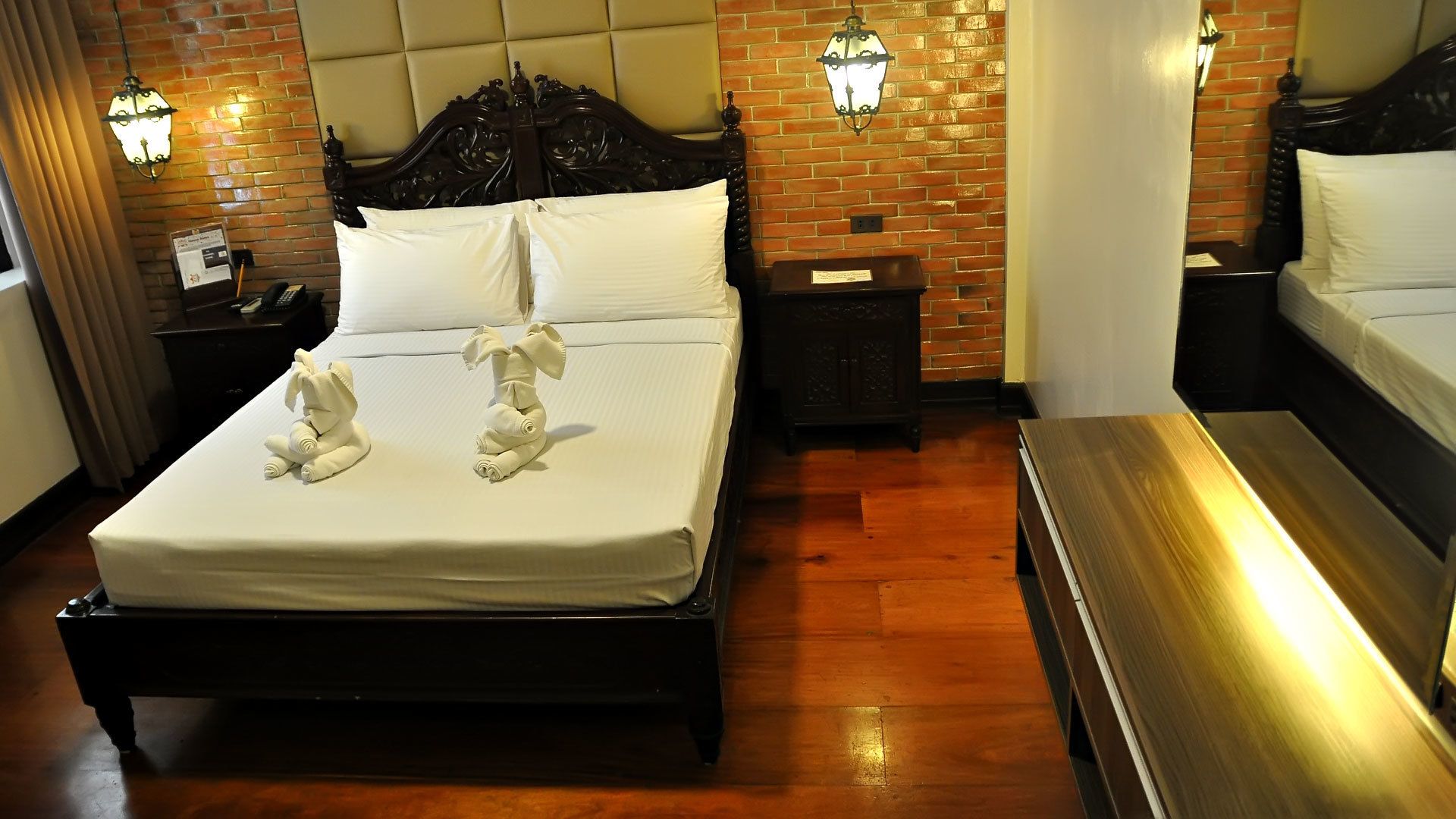 A hotel room with a large bed, a wooden bench, and two nightstands with lamps.