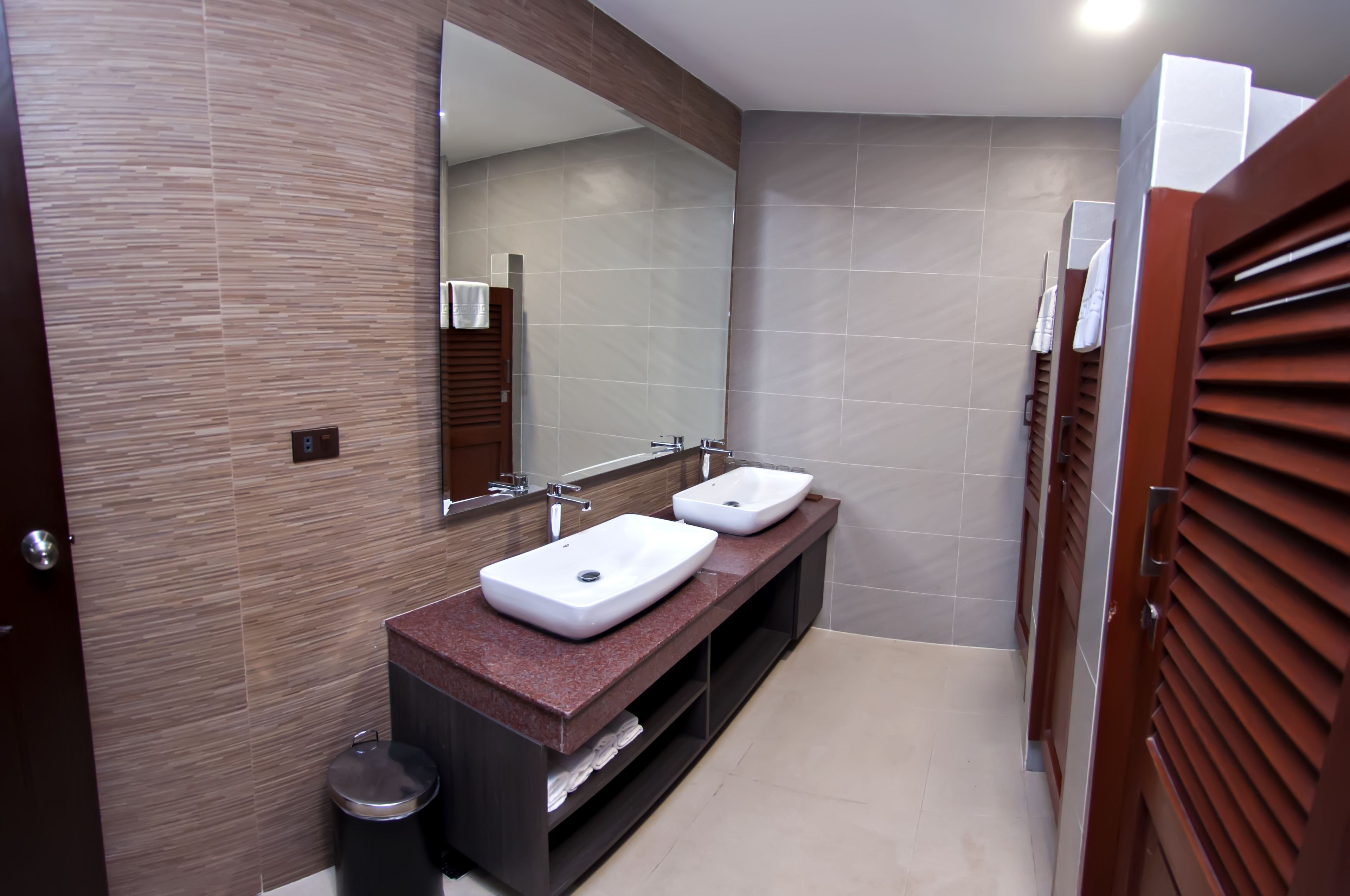 A modern bathroom with two sinks, a large mirror, and wooden paneling.