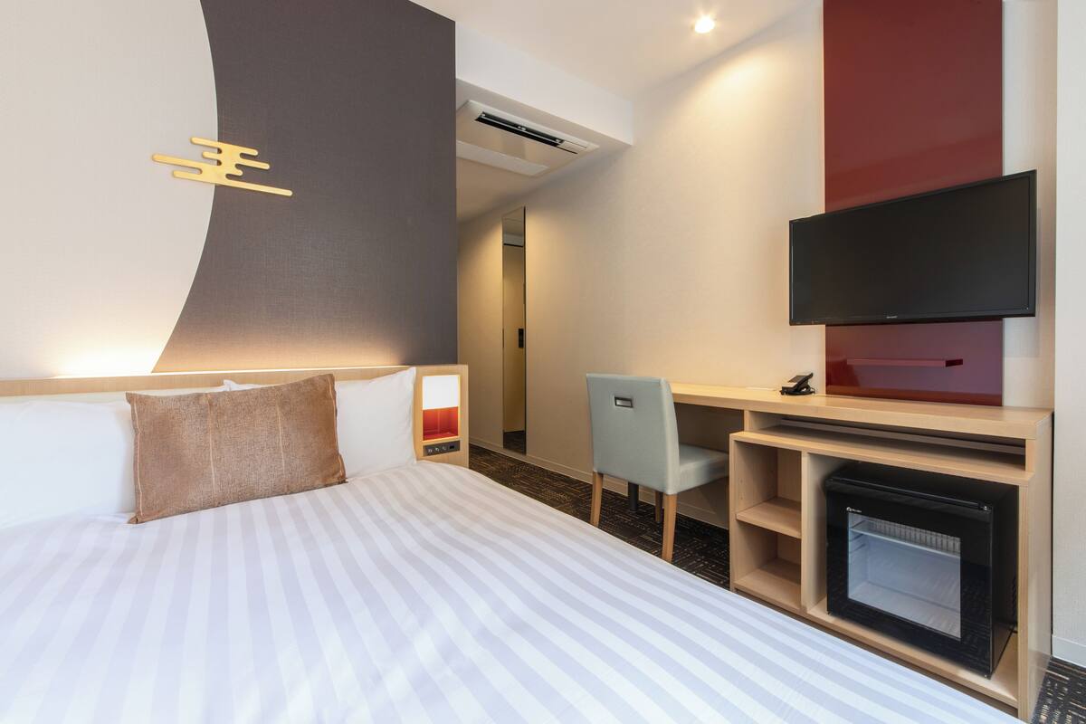 Habitación de hotel con cama, escritorio, silla, televisor de pantalla plana y chimenea.