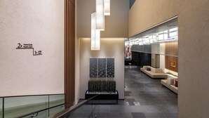 Un moderno hall con barandilla de vidrio, una zona de estar con sofás y un mostrador de recepción.