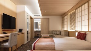 Una habitación de hotel con cama, escritorio, silla, televisor y sofá.