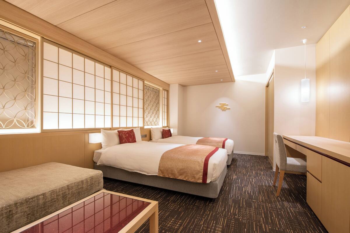 Una habitación de hotel con dos camas, un escritorio y un pequeño rincón de descanso.