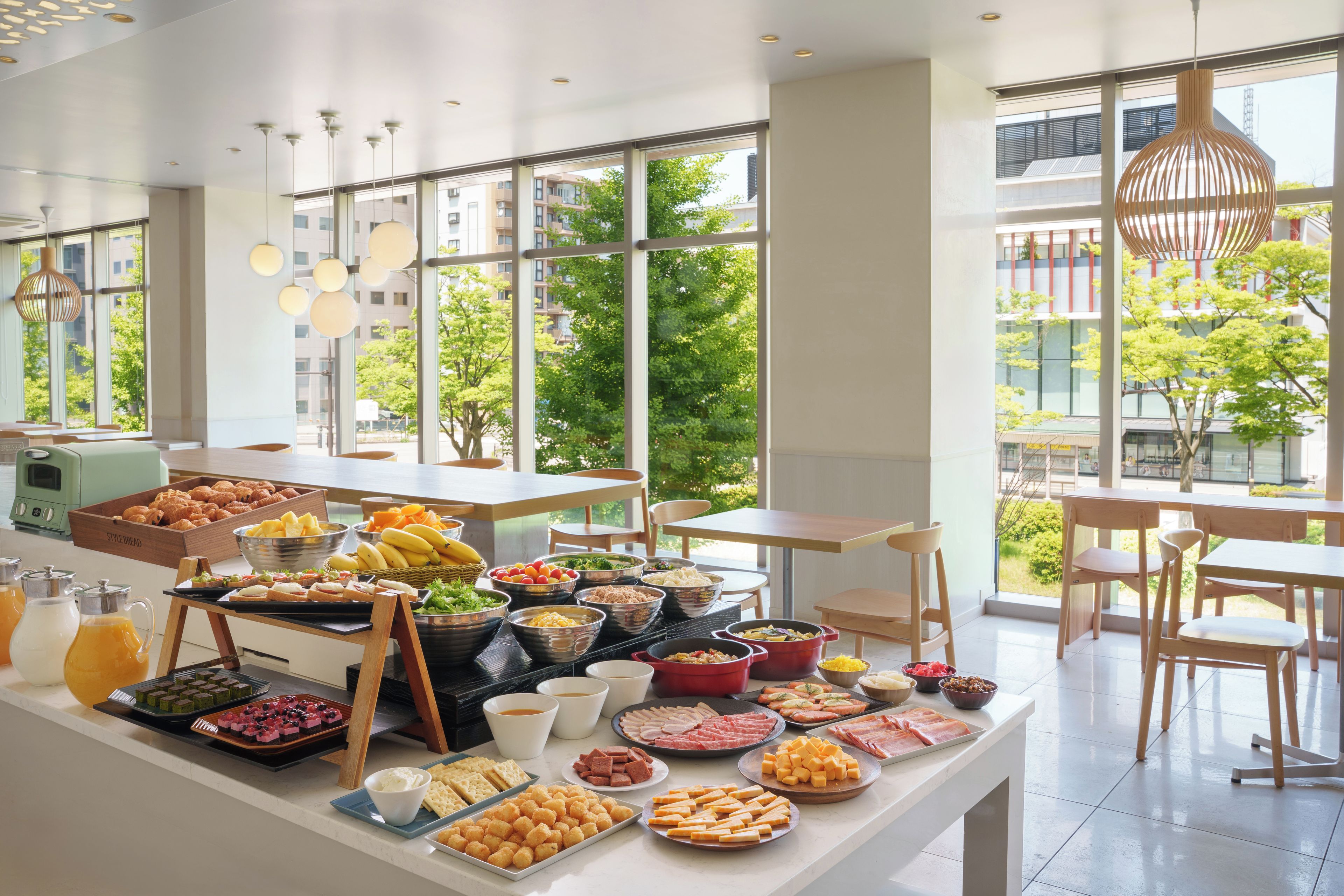 A buffet setup with various food items and a modern interior with large windows.