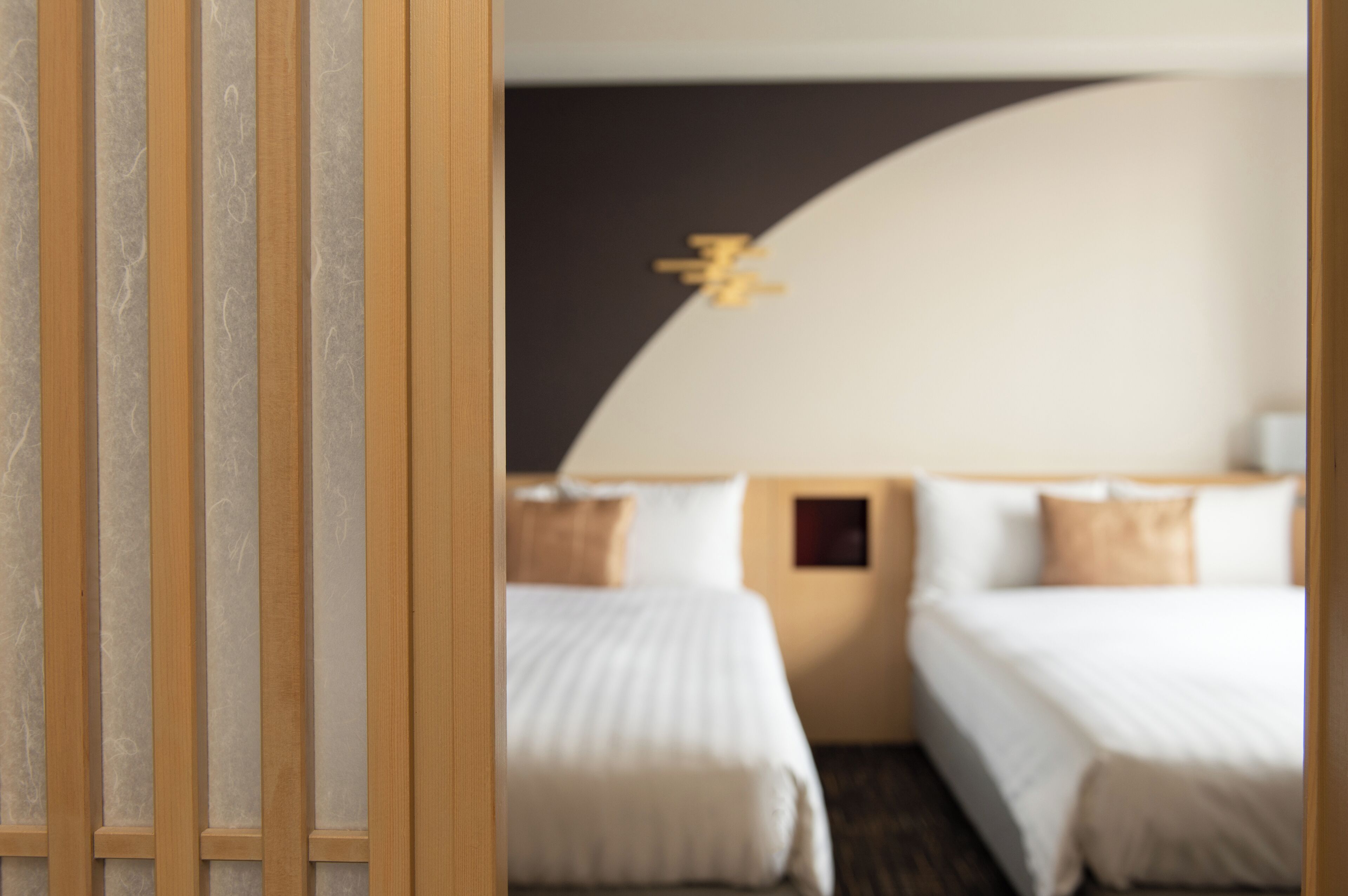 A hotel room with two beds, a wooden partition, and a modern design.