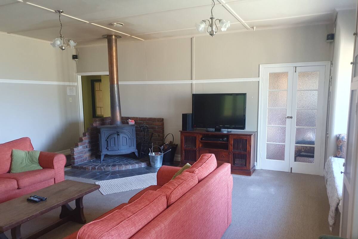 A living room with a brick fireplace, a television on a wooden stand, and two red sofas.