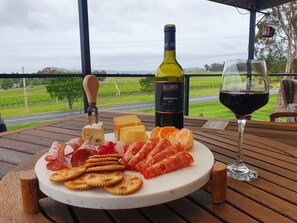 A cheese board with various cheeses, crackers, and cured meats on a wooden table with a wine bottle and glass.
