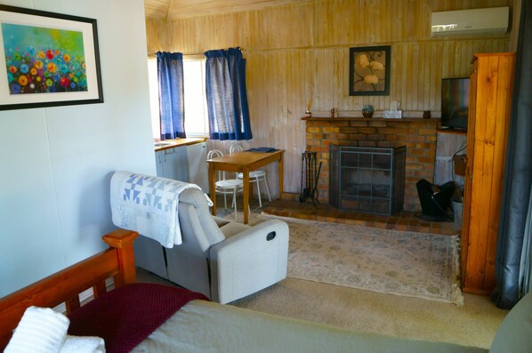 Una habitación acogedora con una cama, una mesita, una chimenea y un televisor.